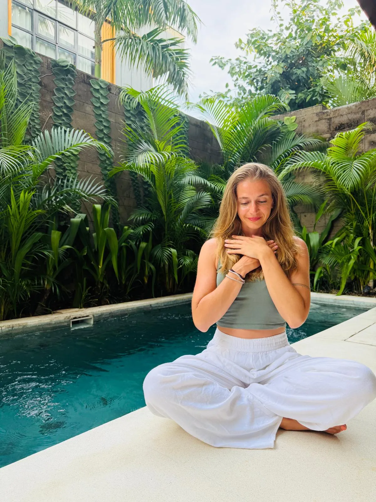 Ramona sitzt am Pool, Hände aufs Herz gelegt.